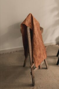 A cozy rustic wooden chair with a soft orange fabric draped over it, creating a warm, inviting atmosphere.