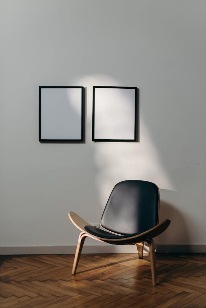 Stylish minimalist interior with black chair and blank frames casting shadows.